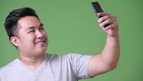 Young-handsome-overweight-Asian-man-against-green-background