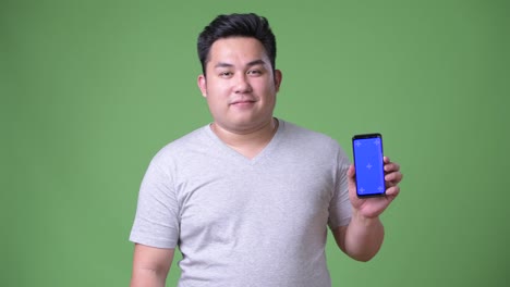 Young-handsome-overweight-Asian-man-against-green-background