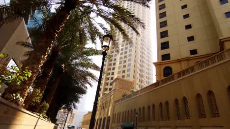 Wide-road-with-tall-palms-and-modern-buildings.-Stock.-Palm-trees-and-typical-retro-art-deco-style-buildings