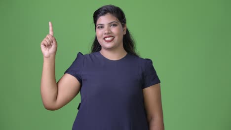 Young-overweight-beautiful-Indian-businesswoman-against-green-background