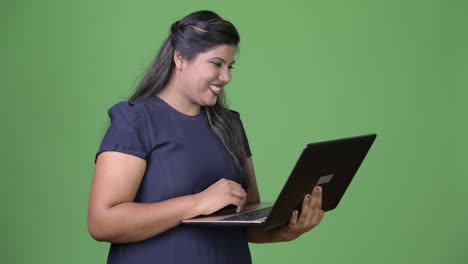 Young-overweight-beautiful-Indian-businesswoman-against-green-background