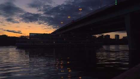 Blick-auf-die-Stadt-bei-Sonnenuntergang-mit-einem-Schiff-unter-der-Brücke