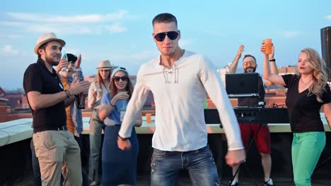 Active-European-man-in-sunglasses-having-fun-dancing-in-the-middle-of-dance-floor-at-rooftop-party