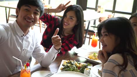 Young-Asian-people-taking-selfie-photos-and-having-lunch-together-at-restaurant-while-they-keep-changing-poses