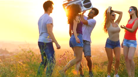 Die-jungen-Leute-mit-einem-Boom-Box-auf-einen-Sonnenuntergang-Hintergrund-tanzen.-Slow-motion