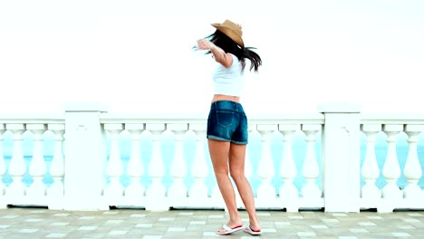 Slow-motion-shot-young-pretty-woman-in-sunglasses-and-hat-having-fun-and-dancing-on-waterfront