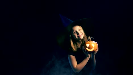 Girl-wearing-black-witch-hat-holding-jack-o'-lanterns