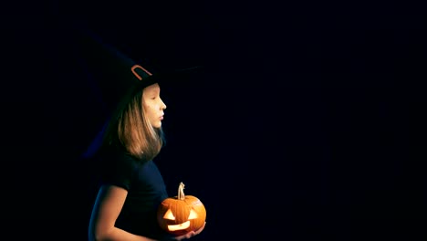 Girl-wearing-black-witch-hat-holding-jack-o'-lanterns