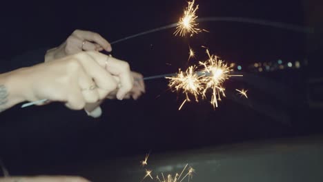 Close-up-slow-motion-shot-of-girls-hands-playing-with-sparklers-at-night