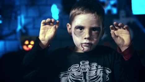 Beängstigend-kleiner-Junge-Schädel-geschminkt-für-Halloween-mit-Fingern-zu-erschrecken
