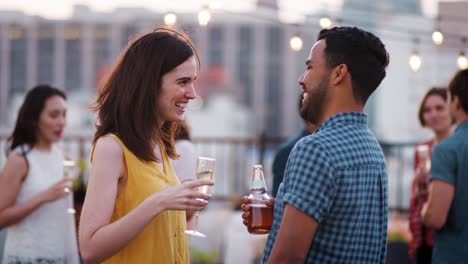 Freunde-versammelt-auf-Dachterrasse-für-Party-mit-Skyline-der-Stadt-im-Hintergrund