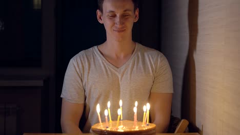 Young-man-blows-out-candles-on-a-festive-cake