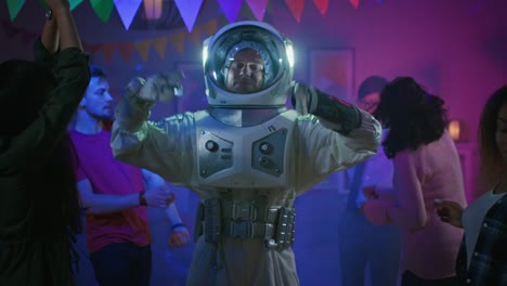 At-the-College-House-Costume-Party:-Fun-Guy-Wearing-Space-Suit-Dances-Off,-Doing-Groovy-Funky-Robot-Dance-Modern-Moves.-With-Him-Beautiful-Girls-and-Boys-Dancing-in-Neon-Lights.-In-Slow-Motion.