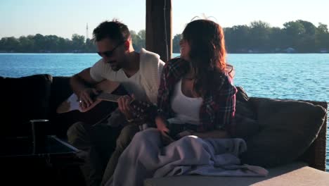 Couple-talking-while-man-is-holding-guitar-by-the-river