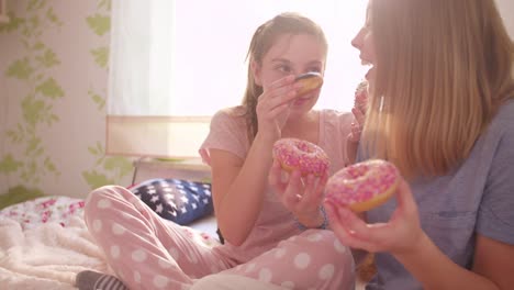 Riendo-teen-girls-compartir-rosquillas-en-un-amplio-dormitorio