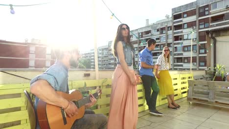 Músico-tocando-la-guitarra,-cantando-junto-a-él,-gente-que-habla-en-el-fondo-de-la-mujer