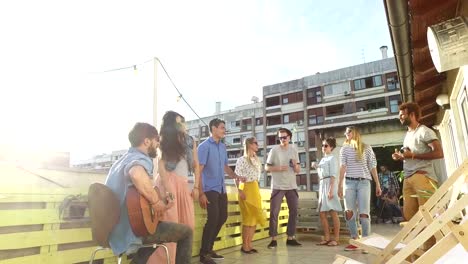 Happy-people-dancing-and-playing-guitar-at-the-rooftop-party-on-sunny-day