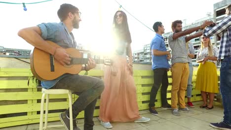 Músico-tocando-la-guitarra,-grupo-de-personas-tomando-fotos-en-la-fiesta-en-la-azotea