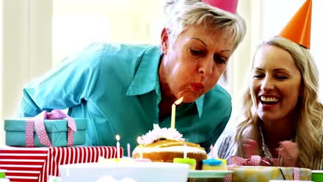 Senior-woman-blowing-out-the-candles-on-a-birthday-cake