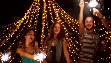 Happy-friends-dancing-with-sparklers-at-night-party