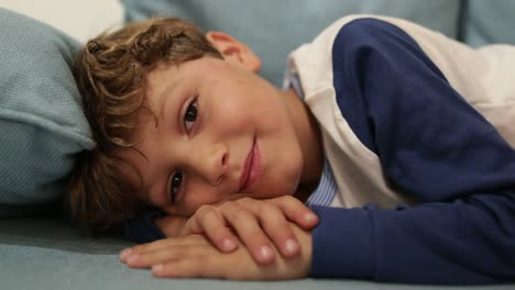 Cute-handsome-child-looking-to-camera-casually-candidly-lying-down-in-living-room-sofa-in-4K