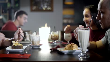 jóvenes-están-comiendo-deliciosos-postres-y-beber-café-y-cócteles-en-un-restaurante-en-la-noche