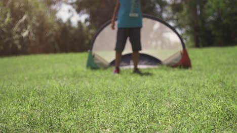 Niños-felices-en-el-campamento-de-verano-jugando-fútbol-coinciden-en-los-niños-de-campo-de-pasto-verde-patadas-pena-portero-lenta