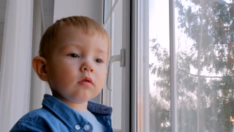 Nachdenklich-kleiner-Junge-Blick-durch-Fenster