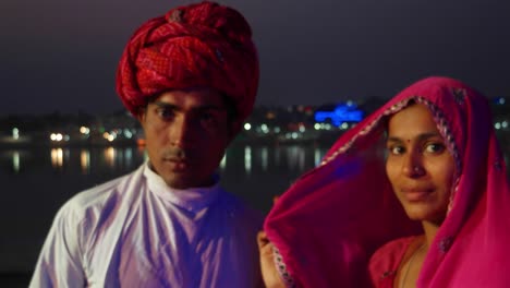 Portrait-of-an-Indian-couple-against-the-background-of-lights-reflecting-on-the-holy-lake-of-Pushkar,-Rajasthan