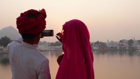 Pan-links-nach-Paar-in-indischen-Kleid-Fotografieren-von-Sonnenuntergang-an-einem-heiligen-See-in-Rajasthan