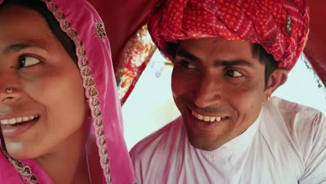 Pareja-de-Rajasthani-en-vestido-étnico-disfrutando-de-un-camello-viajar-en-una-caravana-en-la-Feria-de-Pushkar,-Rajasthan,-India