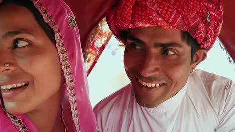 Rajasthani-couple-in-ethnic-dress-enjoying-a-camel-ride-in-a-caravan-at-Pushkar-Fair,-Rajasthan,--India