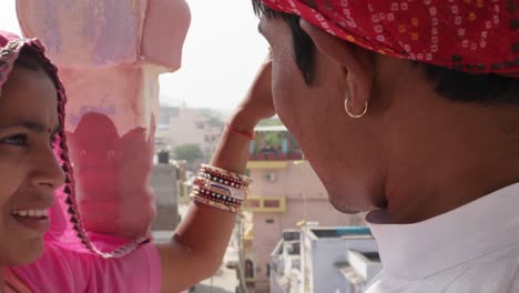 Indian-couple-in-traditional-dress-make-heart-symbol-with-fingers-and-hand,-looking-down-from-a-vantage-point-at-Pushkar-Mela-festival-in-Rajasthan,-India