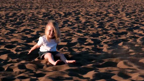 Bella-feliz-poco-chica-rubia-jugando-y-tirando-arena-en-la-playa.