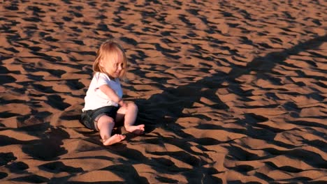 Girl-playing-in-the-sand-sitting-on-the-beach.