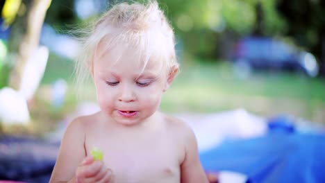 Little-Girl-with-blonde-hair-eagerly-eating-grapes-outdoors