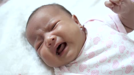 A-newborn-girl-is-crying-laying-on-the-white-cloth.