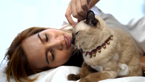 Happy-Asian-woman-lying-on-bed-with-her-lovely-cats.