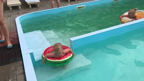 Un-niño-y-una-niña-adolescente-se-divierten-en-la-piscina-en-círculos-inflables.