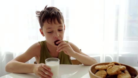 Junge-Essen-hausgemachte-Kekse-mit-Milch-in-der-Küche-zu-Hause.