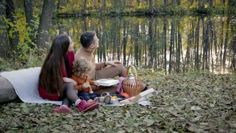 Happy-family-on-picnic-near-lake-in-forest