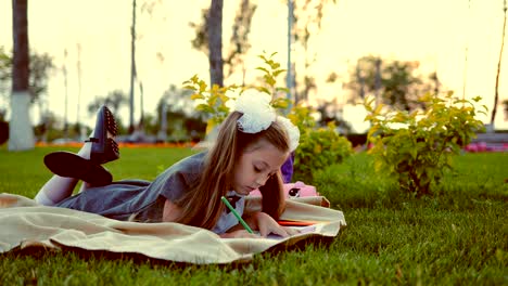 School-girl-painting,-lying-on-the-lawn