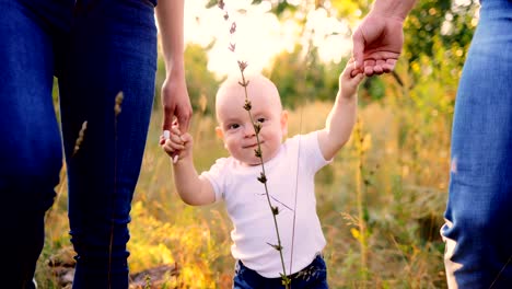 Close-up-portrait-of-the-baby.-Kid-is-walking-on-the-grass-in-the-forest,-parents-are-holding-his-hands