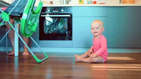 Small-child-is-sitting-on-the-floor-in-the-kitchen