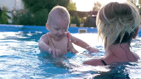 niño-feliz-hacer-salpicaduras-en-piscina,-niño-con-madre-divertirse-en-día-caliente-de-verano