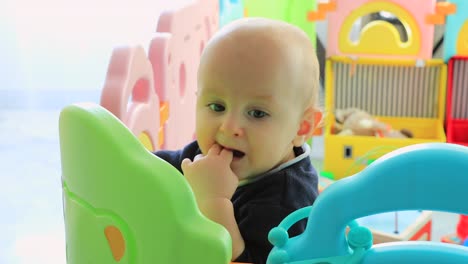 Baby-Boy-Standing-In-Colorful-Playpen