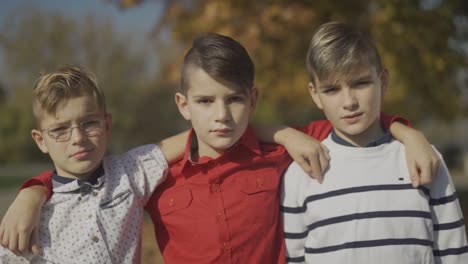 Three-young-boys-embracing-in-the-park.-Little-brothers-spending-time-together-outdoors.