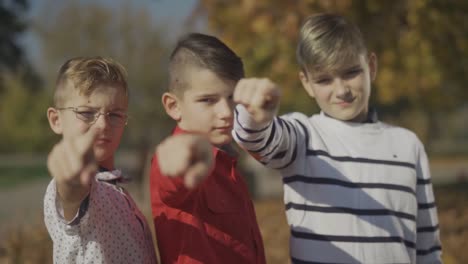 Three-boys-pointing-fingers-at-the-camera.-Brothers-spend-time-together-outdoors.-Focus-moves-from-the-foreground-to-the-background.