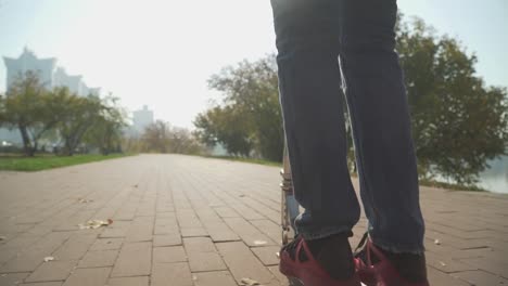 Boy-rides-a-scooter-in-the-park.-The-camera-moves-behind-the-.