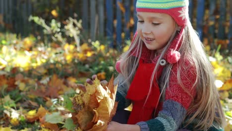 Beautiful,-little-girl-playing-with-autumn,-yellow-leaves-in-the-Park.-The-concept-of-autumn